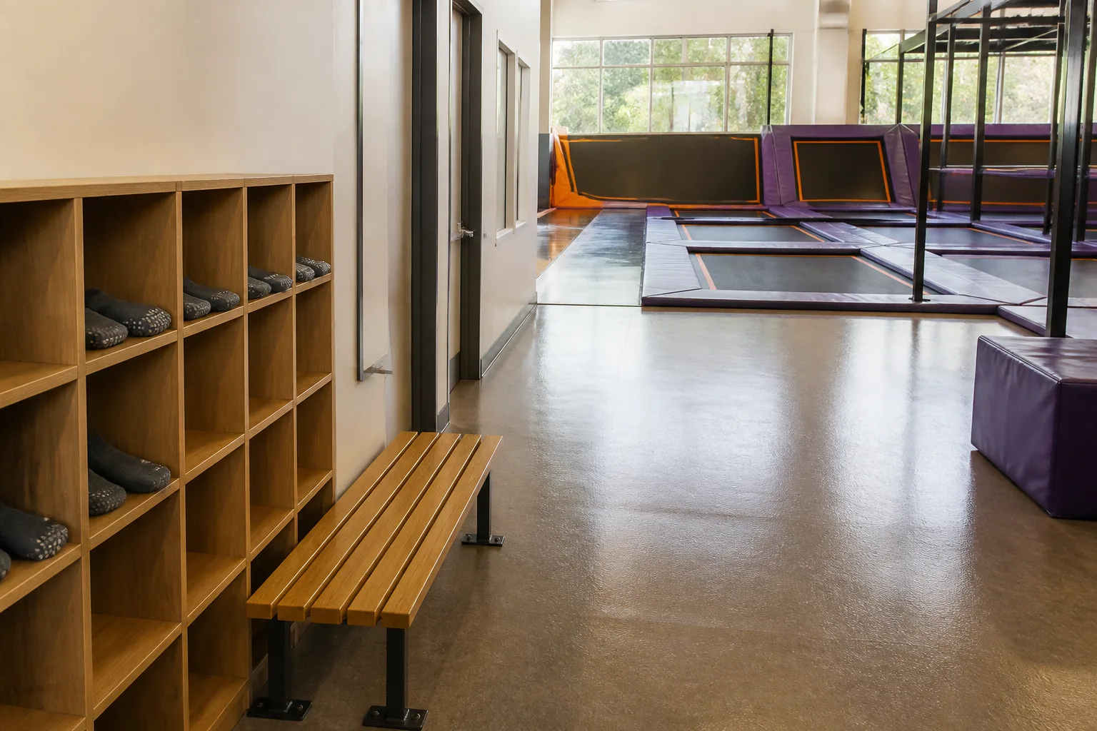 Open cubbies and a bench sit beside a bright trampoline area.