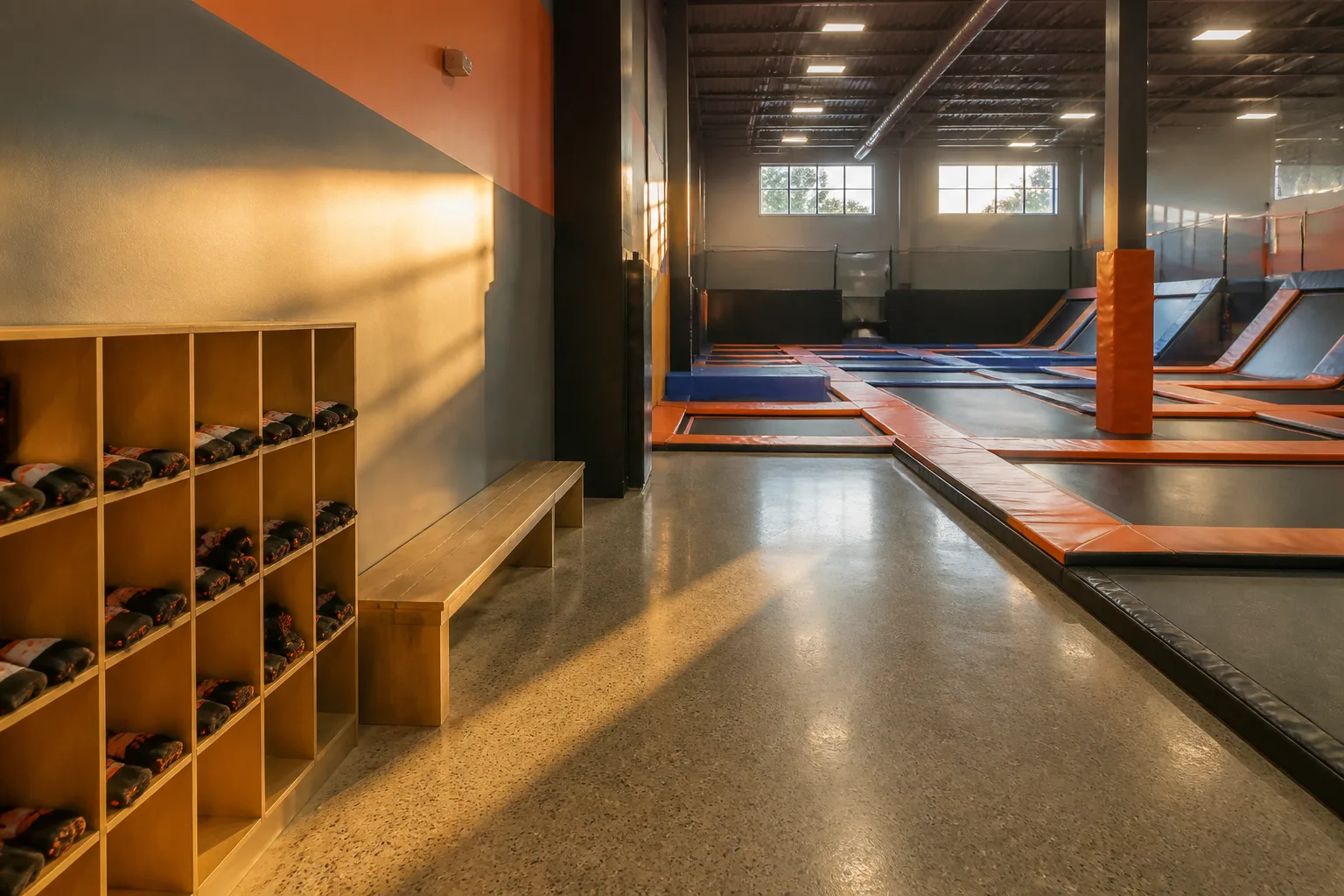 Empty trampoline courts sit beside cubbies and a long bench.