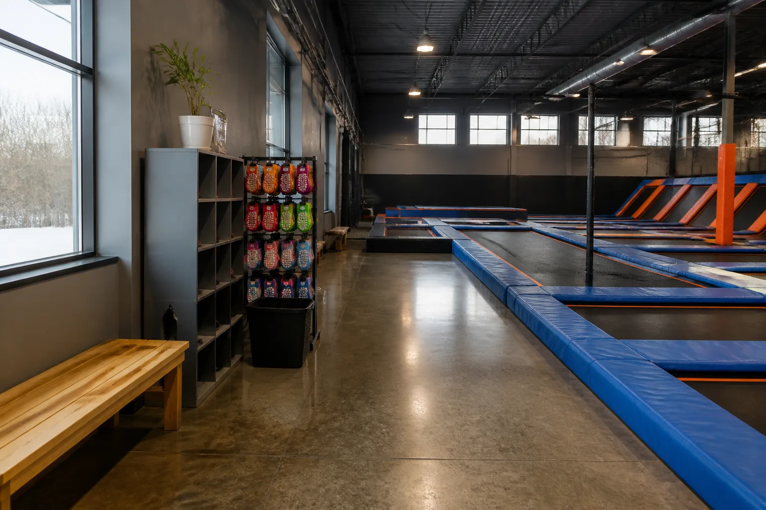 Rows of blue trampoline courts sit under bright indoor lights.