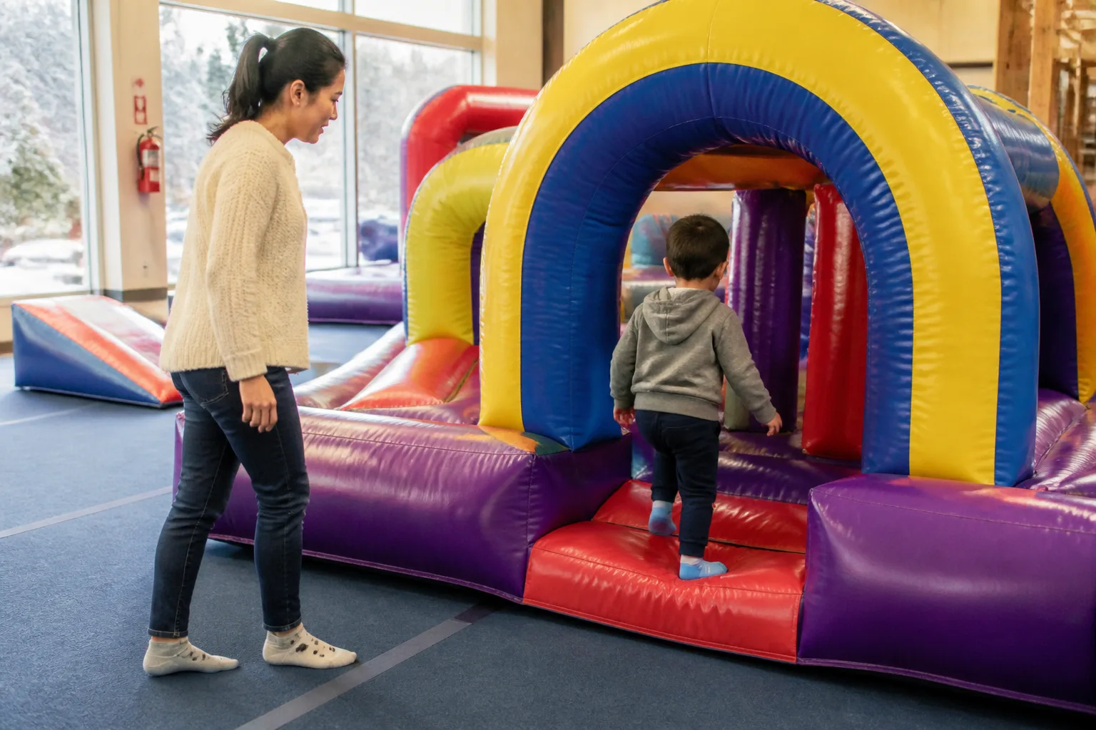 A child enters a small inflatable arch as an adult walks beside him.