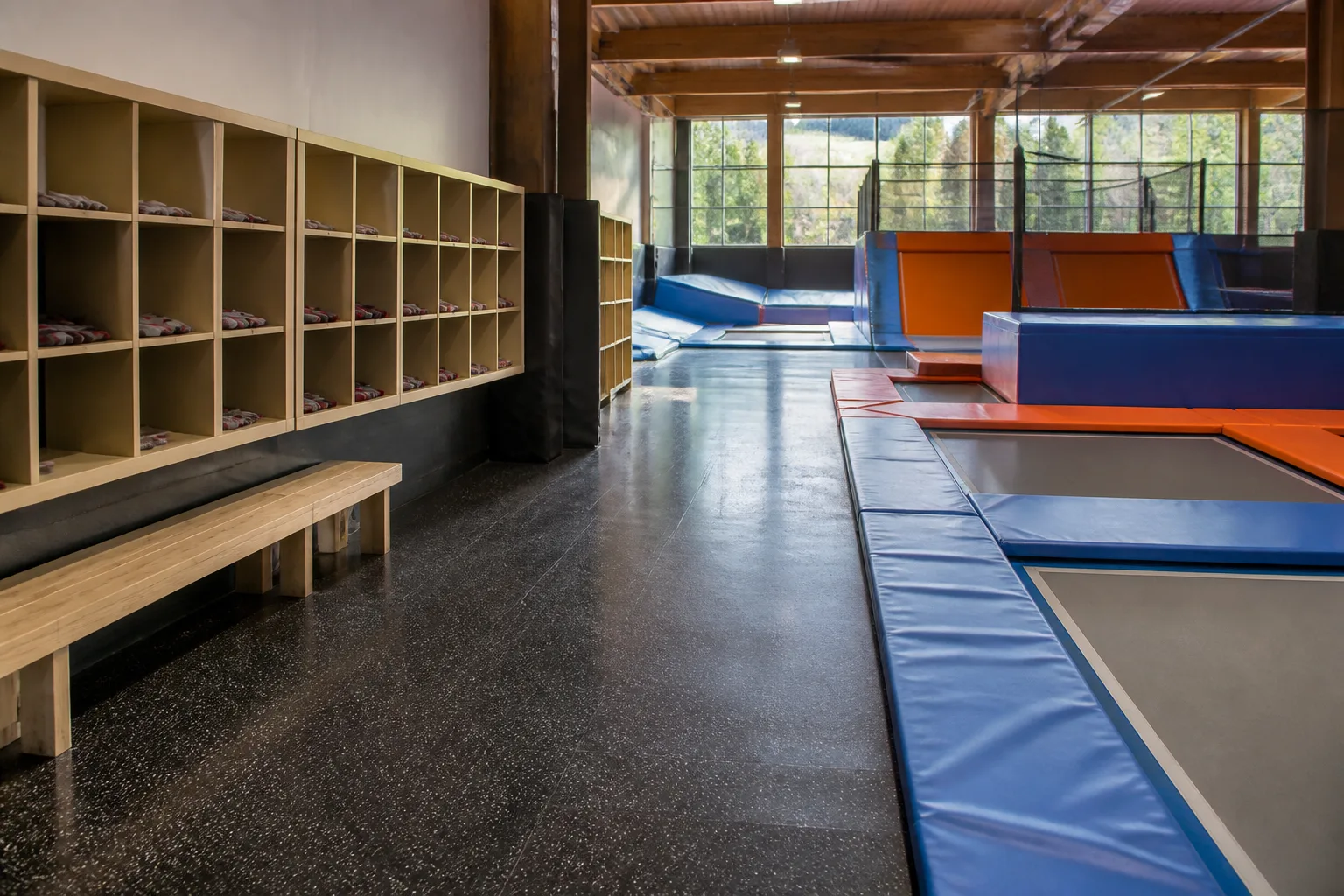 Open cubbies and benches line a trampoline park walkway.
